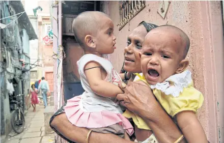  ?? ?? A mother holds two children to have them administer­ed with a polio vaccinatio­n during the Pulse Polio drive in Mumbai, India.