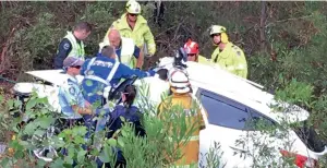  ?? AP ?? Emergency officers work to cut Samuel Lethbridge from the wreck of his car off a highway in New South Wales. —