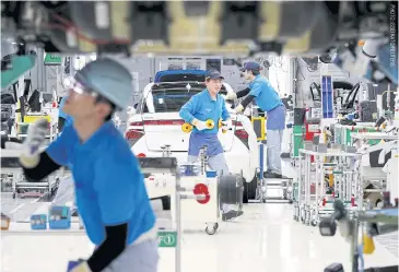  ?? ?? Toyota Motor Corp employees work on the assembly line of a Mirai fuel cell vehicle at the company’s Motomachi plant in Aichi prefecture in Japan.
