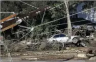  ?? MARCIO JOSE SANCHEZ — THE ASSOCIATED PRESS FILE ?? A damaged car sits over fallen and debris behind downed power lines in Montecito, Calif. While an aggressive cleanup could mean Montecito will welcome visitors again in weeks, the rebuilding of infrastruc­ture and hundreds of homes will be measured in...