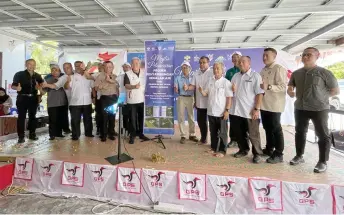  ?? ?? Awang Tengah (left) poses next to the bunting announcing the new water pipeline extension project. Also seen are Hasbi (front row, fifth right) and Paulus on his left.