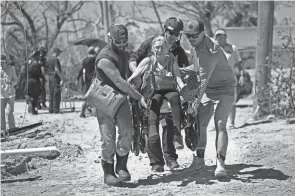  ?? GERALD HERBERT/AP ?? Rescuers help evacuate resident Suzanne Tomlinson to a waiting boat in the aftermath of Hurricane Ian on Pine Island, Florida, on Sunday. The only bridge to the island was impassable after the storm came through.