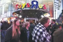  ??  ?? PEOPLE WALK past Toys “R” Us in Times Square the day after Christmas in the Manhattan borough of New York on Dec. 26, 2015