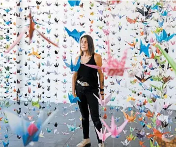  ?? RICHARD VOGEL/AP PHOTOS ?? Karla Funderburk, owner of Matter Studio gallery in Los Angeles, stands among some of the thousands of origami cranes.