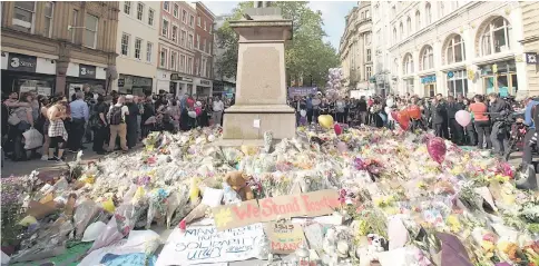  ??  ?? Messages and floral tributes left for the victims of the attack on Manchester Arena lie around the statue in St Ann’s Square in central Manchester. — Reuters photo