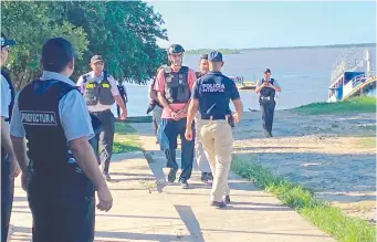  ?? ?? Néstor Horacio Barczuk, esposado, con casco y chaleco, desembarca en el lado paraguayo tras ser cruzado por el río Paraguay.