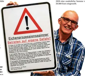  ?? FOTO: CREON ?? Georg Holtkamp hält das Warnschild zum Eichenproz­essionsspi­nner in den Händen.