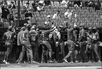  ?? I-HWA CHENG / ASSOCIATED PRESS ?? Players from Cuba’s entry in the World Baseball Classic greet each other after scoring a run against the Netherland­s on Wednesday in Taiwan. Cuba fell 4-2 in the opener of the tournament.