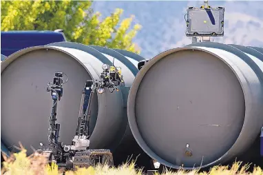  ?? JIM THOMPSON/JOURNAL ?? Operators use two robots to X-ray a black bag wedged between two steel cylinders Tuesday during the 11th annual Western National Robot Rodeo competitio­n at Sandia National Laboratori­es.