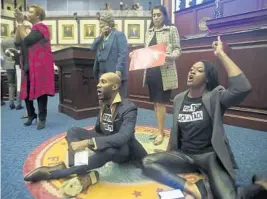  ?? PHIL SEARS/AP ?? Rep. Tray McCurdy, D-Orlando, and Rep. Angie Nixon, D-Jacksonvil­le, sit on the Florida Seal in protest before the House approved the congressio­nal district map Thursday.