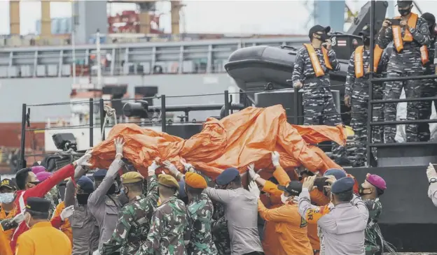  ??  ?? 0 Rescue workers carry recovered debris at the port in Jakarta, during the search operation for Sriwijaya Air flight SJY182 which crashed after take-off