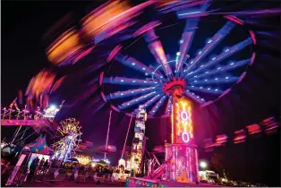  ?? HERALD FILE PHOTO ?? Riders on the Yoyo swings blur past other midway rides and lights during a previous Whoop-Up Days at Exhibition Park.