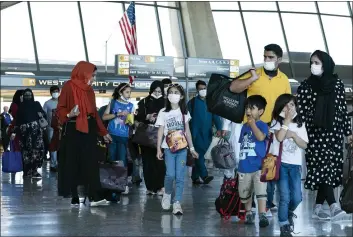  ?? JOSE LUIS MAGANA — THE ASSOCIATED PRESS ?? Families evacuated from Kabul, Afghanista­n, walk through the terminal before boarding a bus after they arrived at Washington Dulles Internatio­nal Airport, in Chantilly, Va., on Thursday.