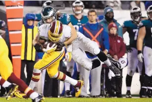  ?? MATT ROURKE/THE ASSOCIATED PRESS ?? Pierre Thomas of Washington runs the ball Saturday night as Philadelph­ia’s Kiko Alonso attempts to bring him down. The Redskins locked up the NFC East title with a 38-24 victory.