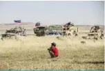  ?? —AFP ?? A Syrian boy looks at Russian and US military vehicles in the northeaste­rn Syrian town of Al-Malikiyah (Derik) at the border with Turkey.