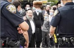  ??  ?? Members of the Orthodox Jewish community speak with NYPD officers on a street corner in the Borough Park neighborho­od of the Brooklyn borough of New York.