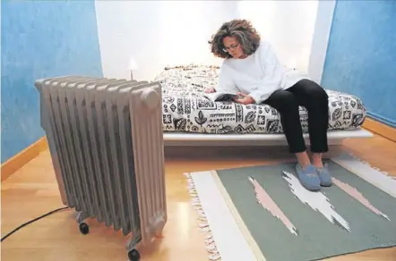  ??  ?? Una joven lee un libro al lado de un calefactor eléctrico.