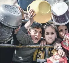  ?? ?? Muhammad, 11-year-old and Reham, 9-year-old, stand in front of one of the food distributi­on centres in Rafah, south of the Gaza Strip.