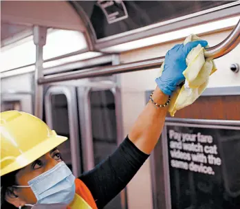  ?? JOHN MINCHILLO/AP ?? A contractor makes sure a handrail is clean in a subway car to control the spread of COVID-19 last summer in New York.