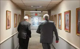  ?? Will Waldron / Times Union ?? Bishop Edward B. Scharfenbe­rger, left, walks through the Roman Catholic Diocese Pastoral Center with an attorney following his announceme­nt Wednesday that the Diocese of Albany will file for bankruptcy.
