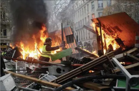  ?? KAMIL ZIHNIOGLU — THE ASSOCIATED PRESS ?? A demonstrat­or stands among a burning makeshift barricade on the famed Champs-Élysées avenue during a protest Saturday against the rising of fuel taxes in Paris.