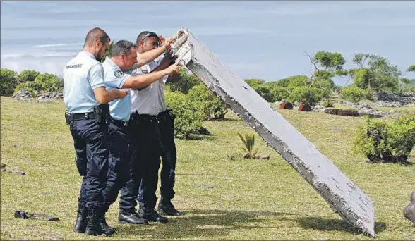  ?? LUCAS MARIE / AP ?? Policías franceses manipulan en Saint André (La Reunión) el flap de un ala encontrado en la playa