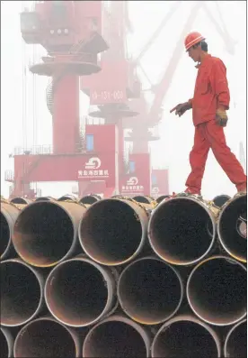  ?? PHOTO: REUTERS ?? A worker walks on steel tubes waiting to be exported at a port in China. The slowdown in the Chinese economy has led to excess stock in the global steel industry.