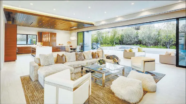  ?? Berkshire Hathaway Home Services ?? A bank of pocket doors open the living room to the outdoor pool area.