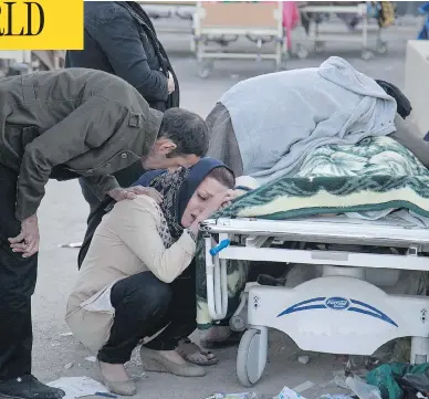  ?? FARZAD MENATI / TASNIM NEWS AGENCY VIA AP ?? Relatives weep over the body of an earthquake victim in Sarpol-e-Zahab, western Iran on Monday. A 7.3 magnitude earthquake struck the Iran-Iraq border region on Sunday night, toppling buildings and killing hundreds.