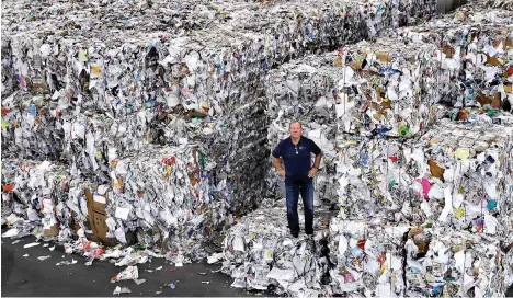  ?? AP Photo/Charles Krupa ?? ■ Ben Harvey, an owner at EL Harvey &amp; Sons, a waste and recycling company, poses on bundles of paper and cardboard on Sept. 6 in Westboroug­h, Mass. The company is currently stacking and holding onto about 2,500 tons of the material, which is awaiting a destinatio­n where a recycler will process the bundles. Recycling programs across the U.S. are shutting down or scaling back because of a global market crisis blamed on contaminat­ion at the curbside bin.