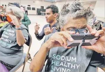  ?? Photograph­s by Luis Sinco Los Angeles Times ?? RYAN ANDERSON, center, helps Sodium Healthy Living Project participan­ts Sandra Goldsmith, 74, left, and Blanche Ross, 83, use their phones to view a virtual reality video that tells them about healthful foods.