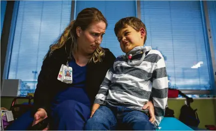  ?? Mark Mulligan / Staff photograph­er ?? Braden Scott, 7, jokes with occupation­al therapist Jamie Beckham as they play Nintendo Wii at TIRR Memorial Hermann.