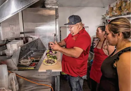  ?? Photos by Carlos Avila Gonzalez/The Chronicle ?? Jessica Osuna (far right) watches husband Mario Bonilla prepare a seafood dish in their food truck Mariscos El Charco in San Jose.