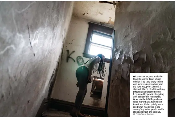  ?? AP Photo/David Goldman ?? n Larrecsa Cox, who leads the Quick Response Team whose mission is to save every citizen who survives an overdose from the next one, peers around a stairwell March 18 while walking through an abandoned home frequented by people struggling with addiction in Huntington, W.Va. As the COVID pandemic killed more than a half-million Americans, it also quietly worsened what was before it the country's greatest public health crisis: addiction and despair.