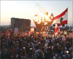  ??  ?? Anti-government demonstrat­ors take pictures of a metal sculpture spelling out the word “revolution” topped by flames during a protest as Lebanese mark one year since the start of nationwide protests, near Beirut’s port, yesterday.