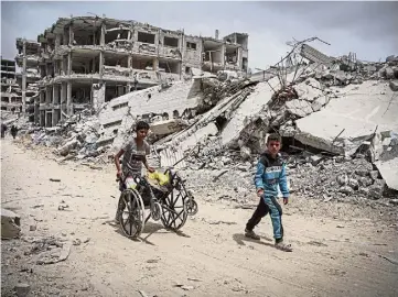  ?? ?? HELL: Palestinia­n children roam the streets of the devastated city of Khan Younis, Gaza.