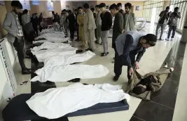  ?? RAHMAT GUL AP ?? Afghan men try to identify the dead bodies at a hospital after a bomb explosion near a school west of Kabul, Afghanista­n, on Saturday.