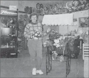  ?? ?? 1998 – Bettin’s Floral has moved to a new location. They are now located where the former JCPenney Catalog store was. This is her working area, but she also shares space in The Linen Closet, which is where Grandma’s Attic was formerly located. Owner Cheryl Olson is pictured above getting ready for spring with this floral display.