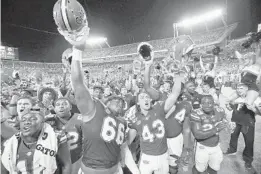  ?? STEPHEN M. DOWELL/ORLANDO SENTINEL ?? Florida players celebrate after slipping past Miami on Saturday night at Camping World Stadium.