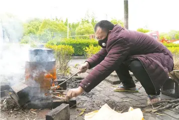  ?? ?? Truck driver Li San cooks a meal over small fires stoked by tree twigs.