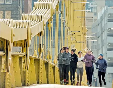  ?? Darrell Sapp/Post-Gazette ?? Runners from Stonehill College in Easton, Mass., jog Thursday across the Roberto Clemente Bridge, Downtown. They are in Pittsburgh for the cross-country portion of the 2018 NCAA Division II National Championsh­ip Festival. Six events are being held this week at different venues in the city.