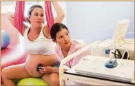  ??  ?? Eine Hebamme betreut eine schwangere Frau, hört die Herztöne des Babys ab.