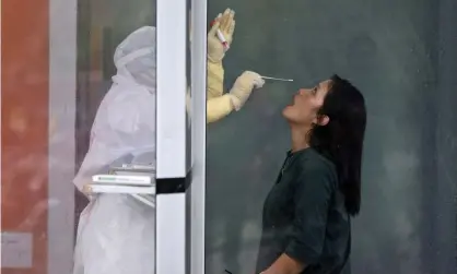  ?? Photograph: Binsar Bakkara/AP ?? ▲ A medical worker prepares to collect nasal swab samples from a woman during a mass test for Covid at North Sumatra University in Medan, Indonesia.