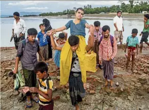  ??  ?? Desperate times: A Rohingya boy carrying his sick sister to a hospital in Teknaf, Bangladesh, alongside other refugees. — AP