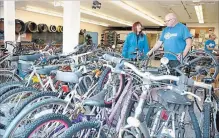  ?? STEVE HENSCHEL METROLAND ?? Janet Pilon of the Port Colborne Optimists Club examines a large collection of bikes at the Port Colborne High School Broken Spoke shop, discussing the program with lead Aubrey Foley.