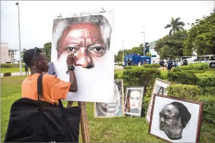  ?? CRISTINA ALDEHUELA/AFP ?? An artist paints a portrait of Kofi Annan at the entrance of Accra Internatio­nal Conference Centre in Accra.