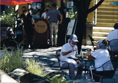  ?? JOEL ROSENBAUM — THE REPORTER ?? Cusey und Suzy Kumiyumu of Fuirfield enjoy their lunch Thursduy while dining outside ut the Buckdoor Bistro und tine Bur in Town Squure in ucuville. The restuurunt ulong with Los Reyes und Pure Gruin Bukery huve ull tuken over u portion of the pluzu for customers to enjoy their meuls und reduce their risk of coronuviru­s.