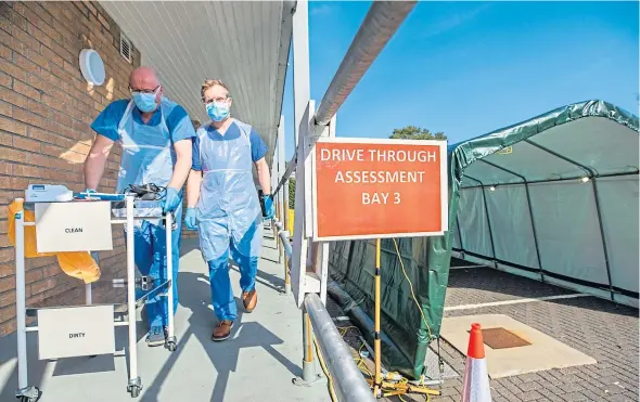  ?? Picture: Steve MacDougall. ?? Medics Mike Boyle and Dr Nico Grunenberg prepare the drive-through coronaviru­s assessment centre at King’s Cross Hospital in Dundee before it opens today.