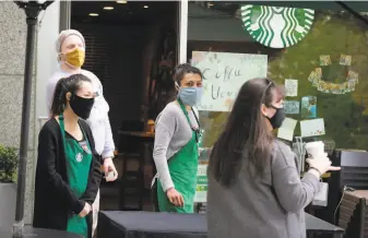  ?? Ted S. Warren / Associated Press ?? Workers at a Starbucks in Seattle serve customers who placed mobile orders outside last week.