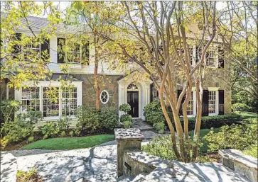  ?? Photograph­s by Simon Berlyn ?? STONE AND SHUTTERS adorn the exterior of the traditiona­l-style home sold by Ashton Kutcher and Mila Kunis. Inside the 7,351-square-foot house, living spaces are dressed in oak f loors and custom moldings.
